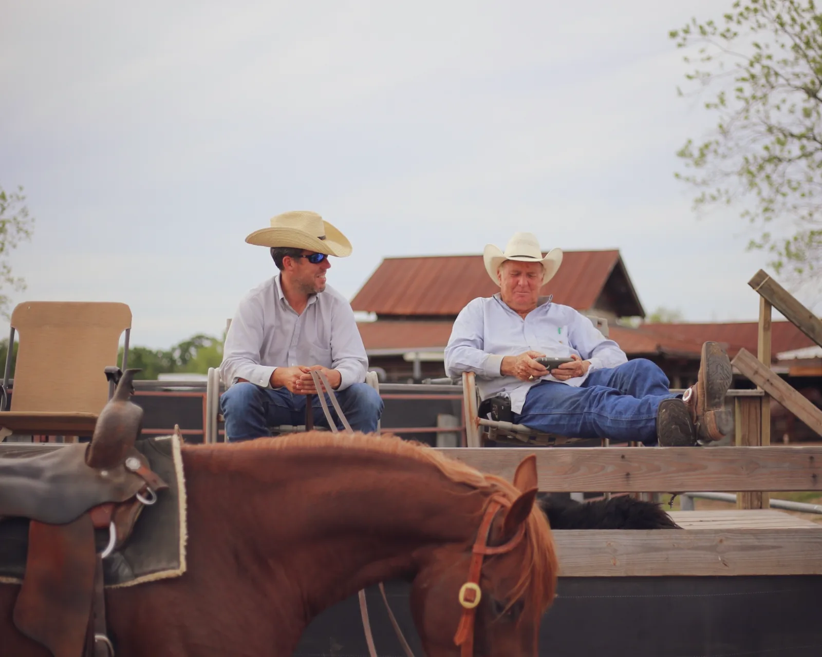 Two men resting by a horse enclosure